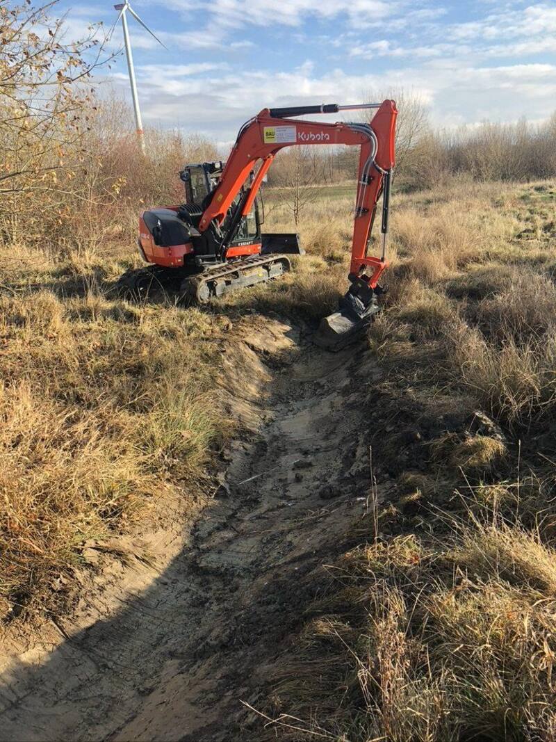 Bagger beim Säubern eines Grabens