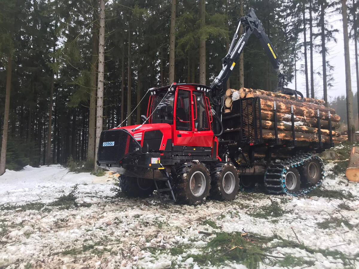 Roter Forwarder mit Langholz im Schnee